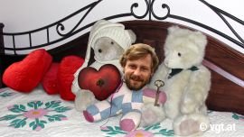 Bett-Szene mit Kuscheltieren und einer Mayr-Melnhof-Puppe, die ein herz und einen Schlüssel hält