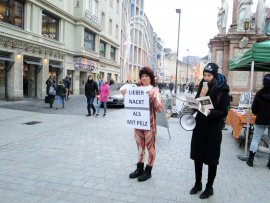 Frau in Bodysuit mit Schild und eine Megafon-Rednerin