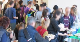 Personen warten darauf sich nach einander Essen aus einem Topf zu schöpfen