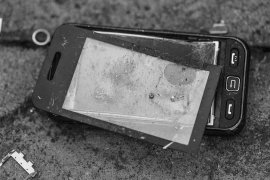 Völlig zerschlagenes Mobiltelefon am Asphalt