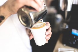 Milch wird in einen Kaffee gegossen