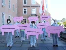 Aktivist:innen halten Pappschweine mit Krankheiten als Aufschrift.