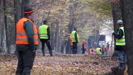Leute in Warnmasken in einer Kolonne vor einem Hochstand