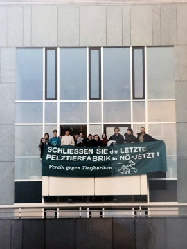 Fassade eines Bürogebäudes, von dem Aktivist:inenn ein Banner halten